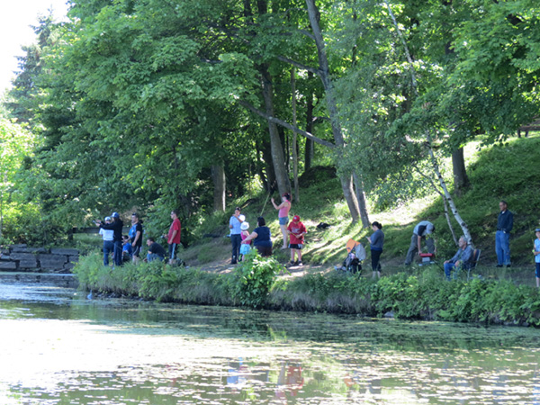 Photo de plusieurs personnes sur la berge d’une rivière en train de pêcher, la photo est prise de l’eau.