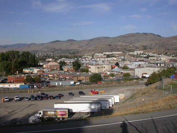 Photo d'une vue de la ville de Vernon : un stationnement, des bâtiments et des montagnes en arrière-plan. 